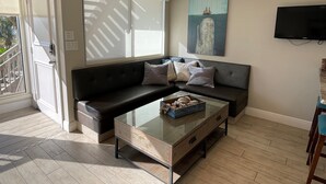 A modern living room with a sectional sofa, a glass coffee table, and a flat-screen TV mounted on the wall. - Exquisite Deluxe beachfront condo (Sarasota)