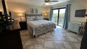 A bedroom with a bed, a nightstand, a dresser, a ceiling fan, and a view of the outdoors. - Cresent Beach Gulf view 2Bd/2Ba Condo (Sarasota)