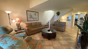 A living room with a sofa, armchairs, a coffee table, and a staircase leading to another level. - Cresent Beach Gulf view 2Bd/2Ba Condo (Sarasota)