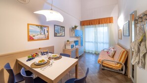 Un comedor con una mesa dispuesta para dos, un sofá y un televisor.