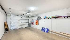 Un garage avec une porte fermée, un ventilateur de plafond et une étagère contenant divers objets, dont un objet coloré.