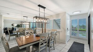 A dining area with a wooden table and chairs, a hanging light fixture, and a view through the window. - 2 Bedroom Beach retreat (Sarasota)