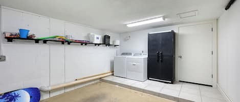 Lavandería con lavadora, secadora y estantes con productos de limpieza.