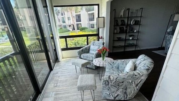 A balcony with a tiled floor, a sofa, a chair, and a small table with a vase of flowers. - Spectacular view on Crescent beach (Sarasota)