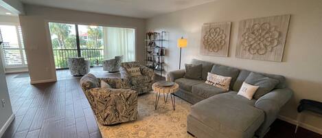 Amplia sala de estar con un sofá gris, sillones estampados y un tapiz decorativo.