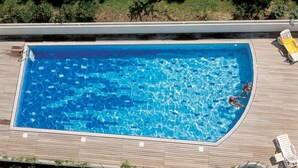 A rectangular swimming pool with clear blue water, surrounded by a wooden deck. - Comfort by the coast - Beahost (Bibione)
