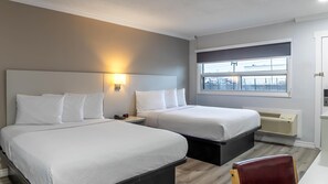 A hotel room with two beds, a nightstand with a phone and lamp, a window with a view of the outside, and a radiator. - Motel 6 – Cornwall, ON (Cornwall)