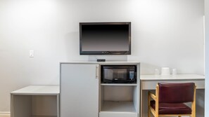 Une petite cuisine équipée d’un four à micro-ondes, d’un petit réfrigérateur et d’un téléviseur fixé au mur juste au-dessus.