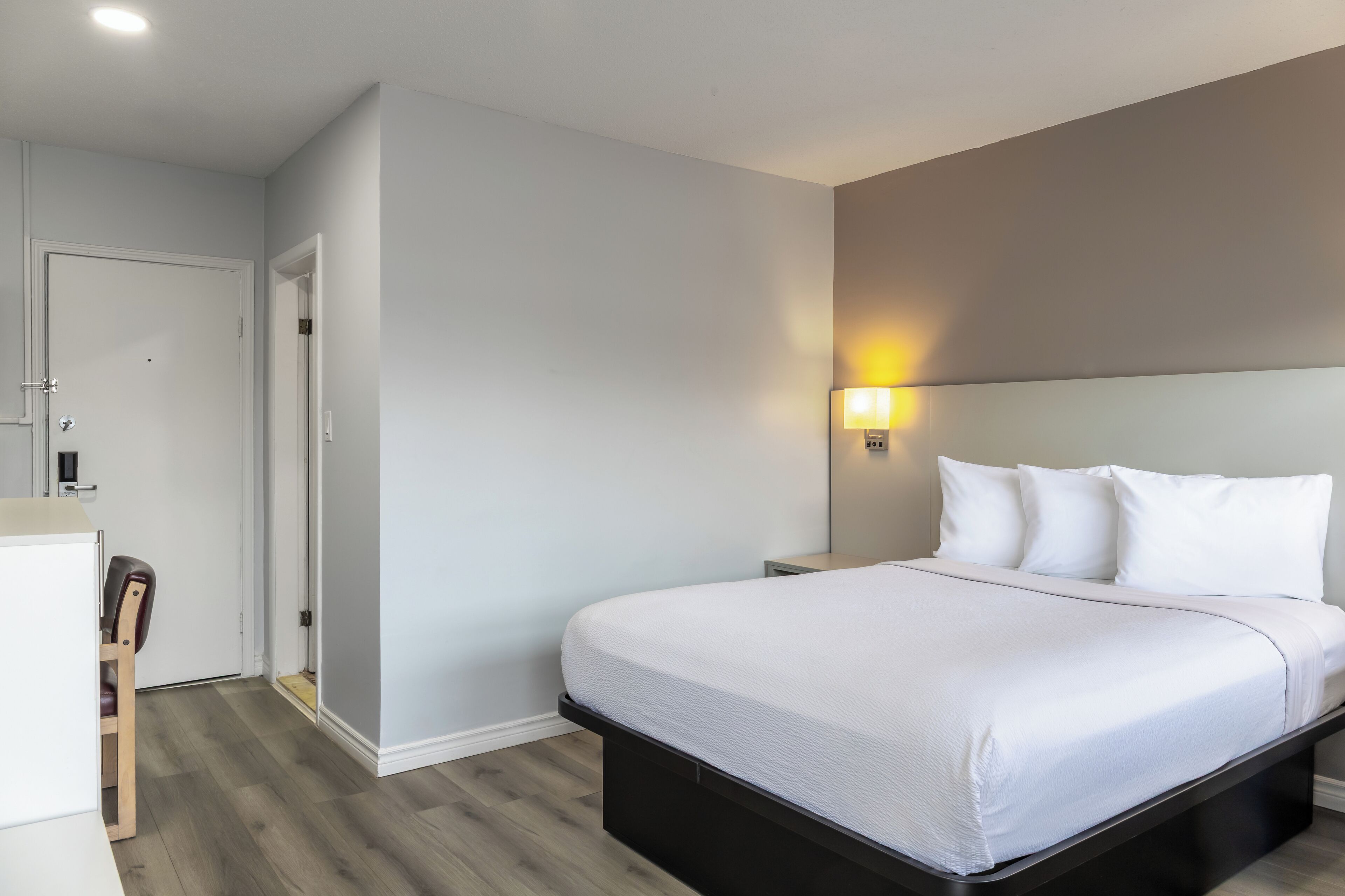 Une chambre d’hôtel moderne avec un grand lit, des tables de chevet et un bureau avec une chaise.