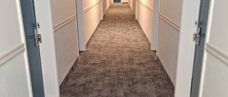A long, narrow hallway with carpeted floors and white walls.
