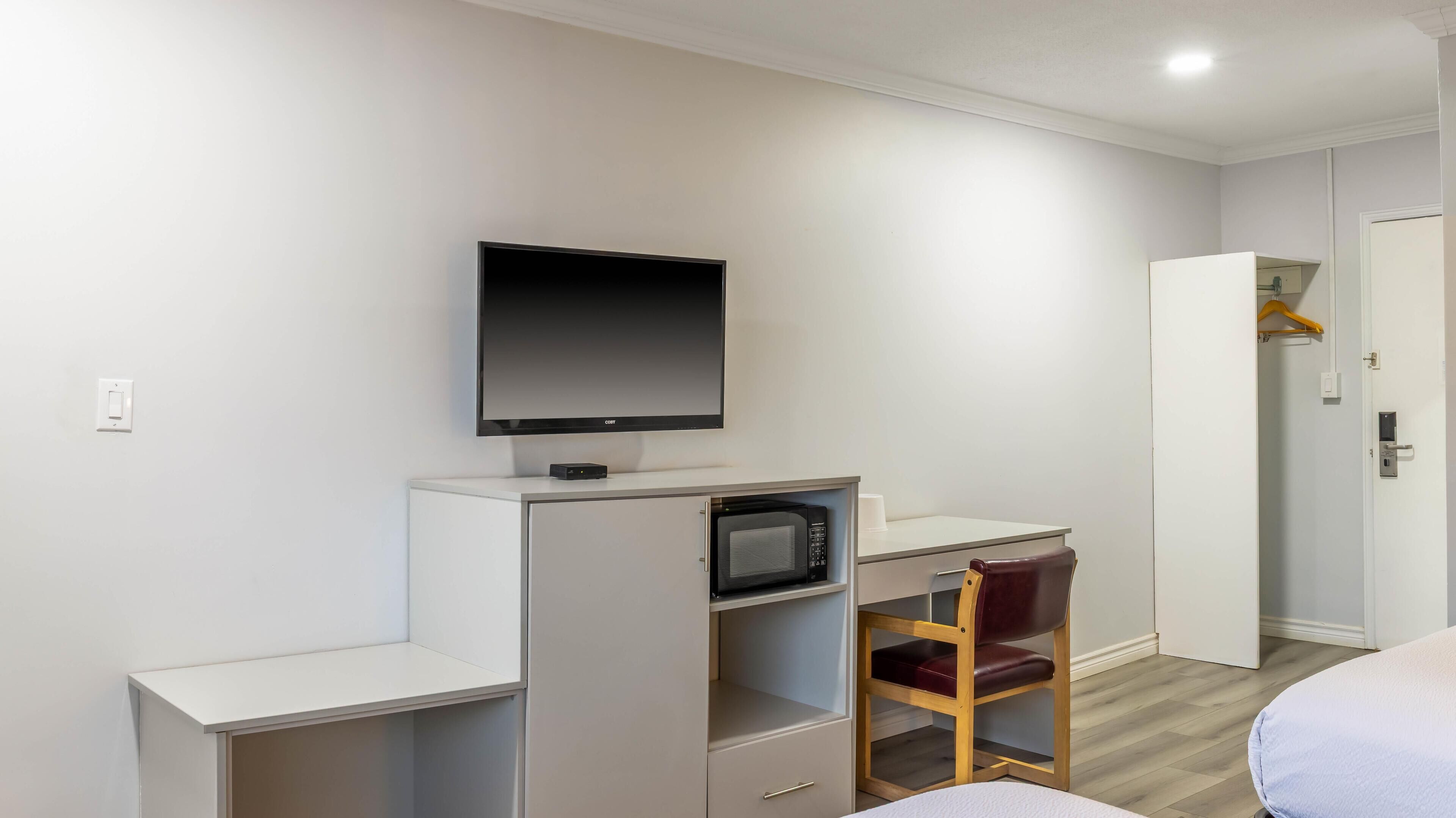 Habitación de hotel con cama, escritorio, televisión de pantalla plana, microondas y armario.