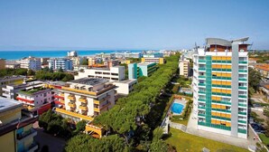 A coastal cityscape with a prominent high-rise hotel featuring balconies and a swimming pool.