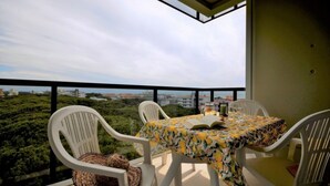 Ein Balkon mit Tisch und Stühlen mit Blick auf Stadt und Grünflächen.