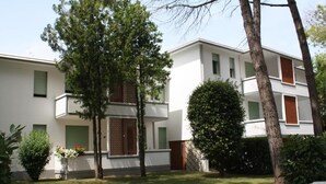 Ein modernes, zweistöckiges Gebäude mit Flachdach, kleinem Vorgarten und weißem Zaun.