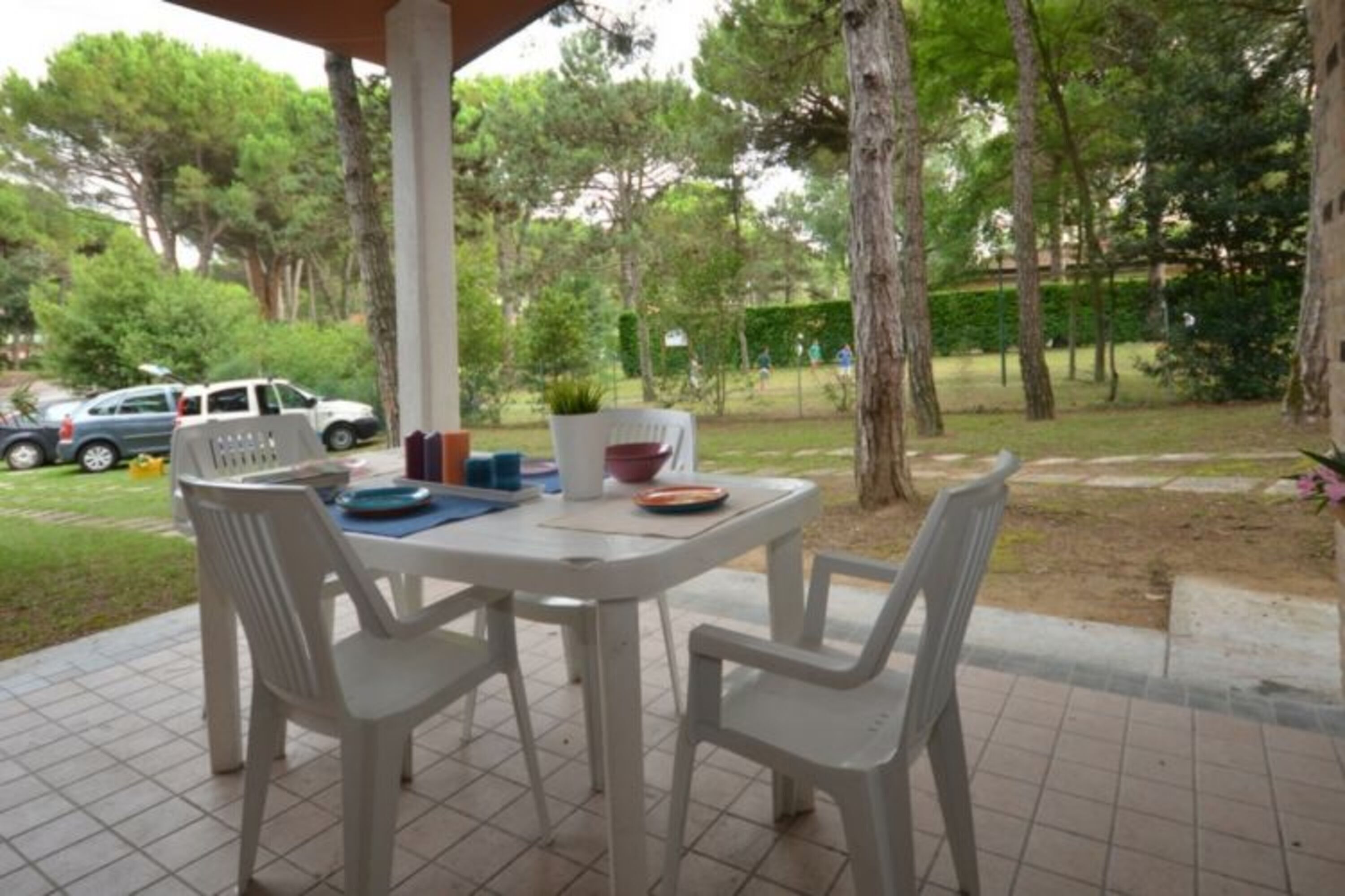 Un'area patio con tavolo e sedie, circondata da alberi e un'auto parcheggiata.