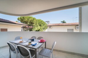 A balcony with a table set for breakfast, chairs, and a view of buildings and trees.
