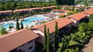 A hotel with a swimming pool, multiple balconies, and a landscaped garden area.
