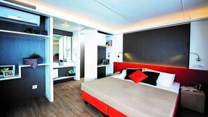 A modern bedroom with a large bed, built-in shelves, and a red accent wall. - ZEcamping 4 étoiles familial pataugeoire animaux acceptés locatif TV clim (Alghero)