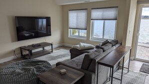 A living room with a flat-screen TV, a sofa, a coffee table, and a view of the sea through large windows. - Luxury Lakefront Escape with Stunning Views at Sparks Marina (Sparks)