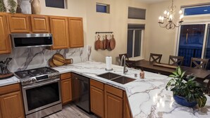 A modern kitchen with wooden cabinets, a stainless steel stove, and a marble countertop. - Luxury Lakefront Escape with Stunning Views at Sparks Marina (Sparks)