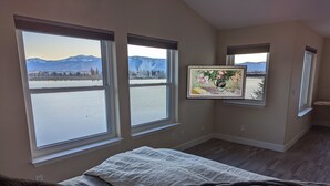 A bedroom with a bed, a large window with a view of mountains and a lake, and a framed picture on the wall. - Luxury Lakefront Escape with Stunning Views at Sparks Marina (Sparks)