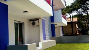 A modern building with a flat roof, a flat facade, and a small front porch with steps leading to the entrance. - Garden retreat steps from the pool (Bibione)