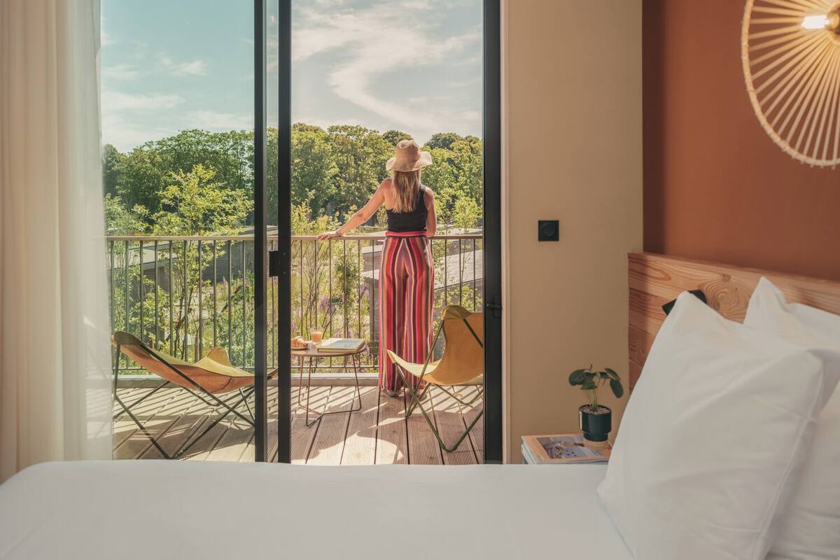 Quarto de hotel com varanda, uma cama, uma cadeira e uma mesa.