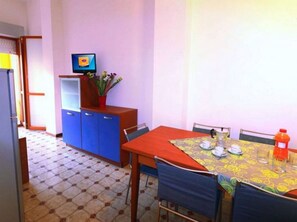A small dining area with a table, chairs, a television, and a cabinet.