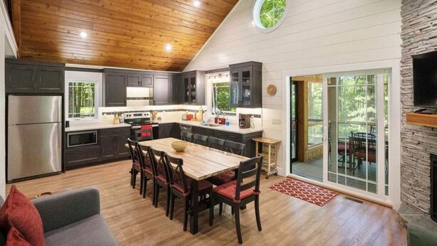 Una cocina moderna con armarios oscuros, techo de madera y chimenea de piedra.