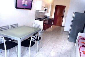 A compact kitchen with a dining table and chairs, a refrigerator, and a microwave. - Poolside comfort in a prestigious location (Bibione)