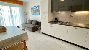 Una cuina moderna amb armaris blancs, una cuina de gas i una zona de dinar amb taula i cadires.
