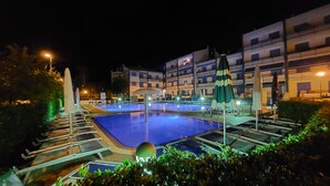 Una piscina amb gandules i ombrel·les, envoltada d'un edifici amb nombroses galeries.