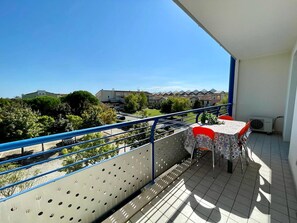 A balcony with a table and chairs, a railing, and a view of buildings and trees. - Luminous flat with balcony (Venice)