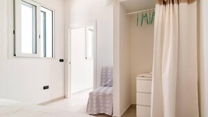A bedroom with a bed, a chair, a wardrobe, and a bathroom. - Serradei House (Torchiarolo)