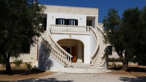 A two-story building with a central staircase leading to an entrance. - Serradei House (Torchiarolo)