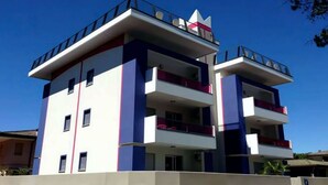 A modern multi-story building with balconies and a flat roof.