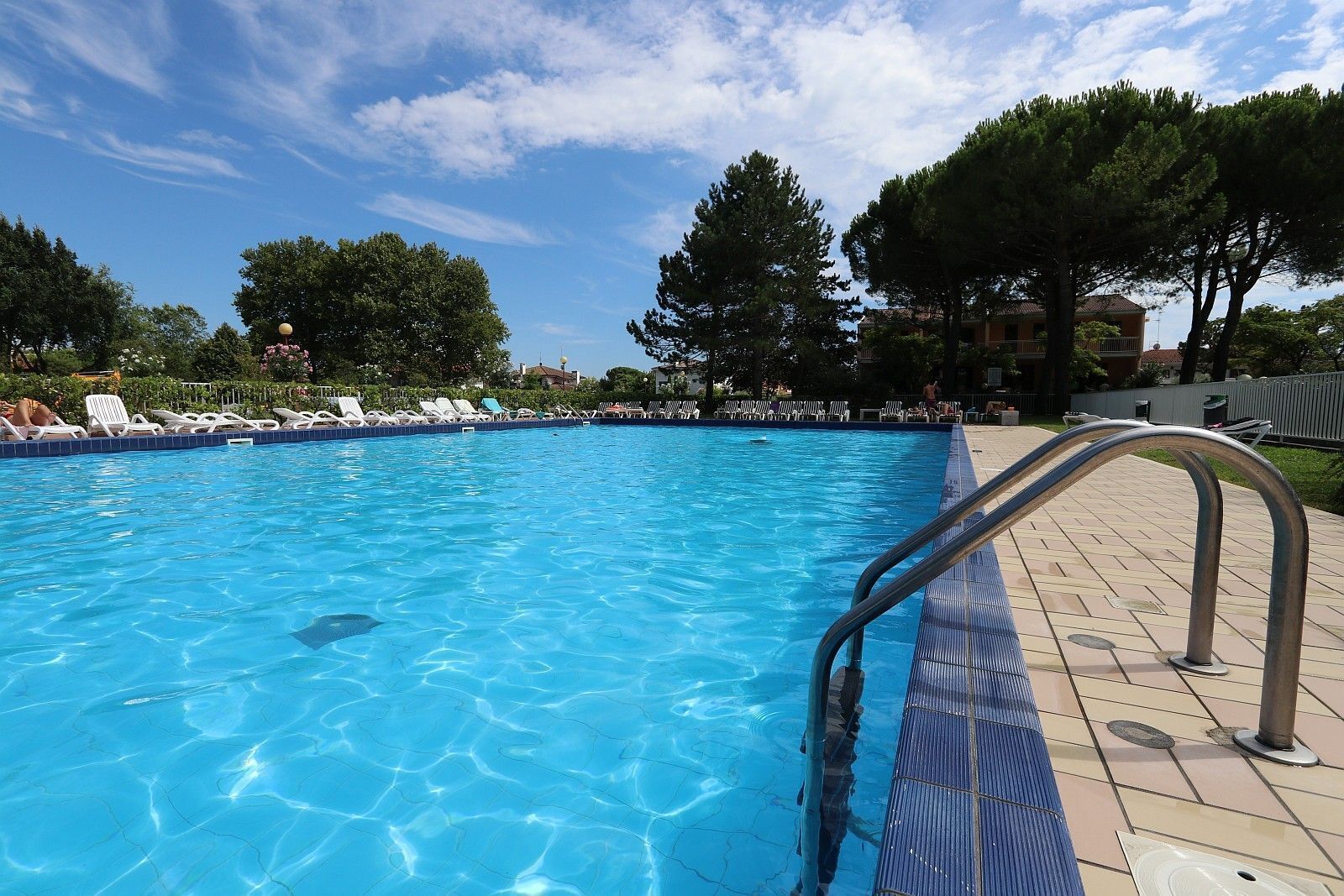 A clear blue pool with lounge chairs and a metal pool ladder.