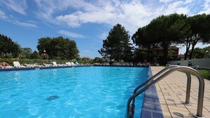 A clear blue pool with lounge chairs and a metal pool ladder. - Quiet villa with private garden (Bibione)