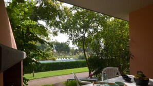 A dining area with a view of a garden and pool. - Quiet villa with private garden (Bibione)
