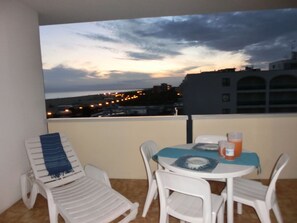 Een balkon met een tafel en stoelen, met uitzicht op een stadsbeeld in de schemering.