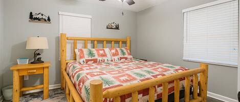 A bedroom with a wooden bed, a nightstand, a ceiling fan, and a window with blinds.