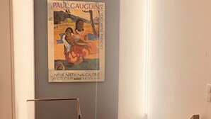 Ein Poster von Paul Gauguins Kunstwerk in einer Diele mit Glastrennwand und Holzboden.