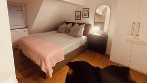 Ein Schlafzimmer mit Bett, Nachttisch, Kleiderschrank und Fenster.