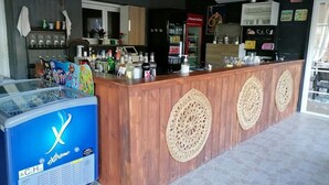 Una zona de bar con mostrador de madera, un refrigerador azul con el rótulo 'Xtreme' y una nevera.