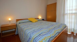 A bedroom with a bed, nightstands, a wardrobe, and a window with curtains.