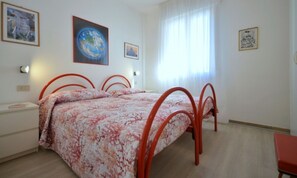Une chambre à coucher comprenant un lit, une table de chevet, une chaise et des œuvres d’art murales.
