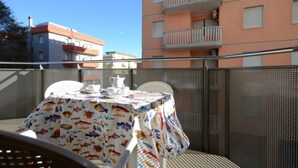 A balcony with a table set for two, chairs, and a railing. - Coastal comfort - Beahost (Bibione)