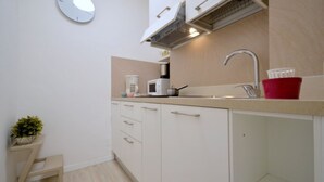 A compact kitchen with a microwave, sink, and cabinets. - Coastal comfort - Beahost (Bibione)