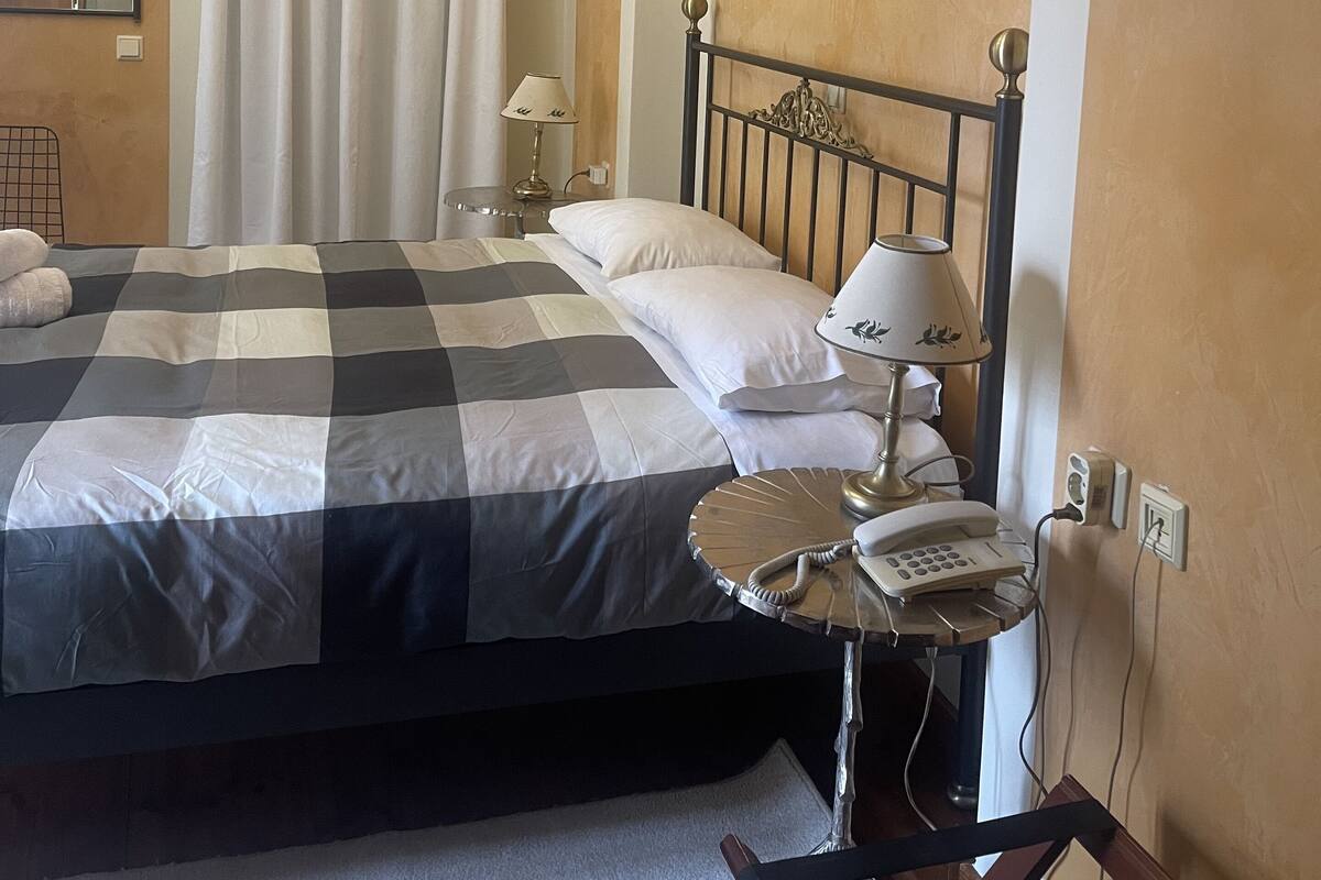 A hotel room with a bed, bedside tables, a lamp, and a telephone.