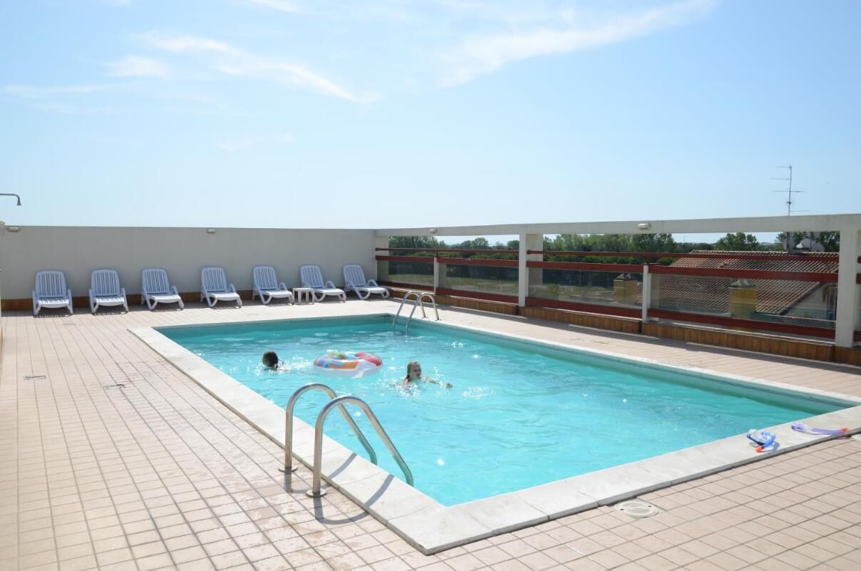 Une piscine avec une terrasse carrelée, quelques chaises longues et un ciel dégagé.